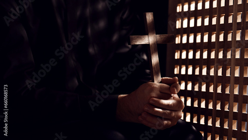 Young priest with cross in confession booth photo