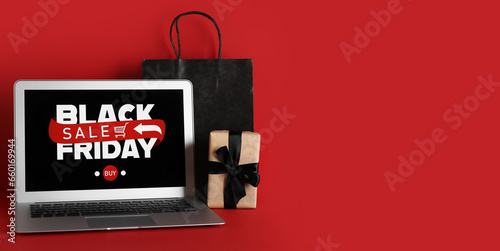 Laptop, shopping bag and gift on red background with space for text. Black Friday sale
