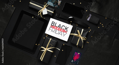 Tablet computer, shopping bag, phone, credit card and gifts on dark background. Black Friday sale