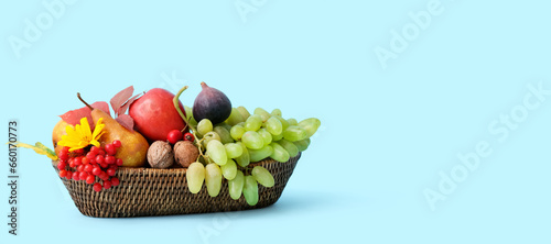 Harvested fruits in wicker basket on light blue background with space for text