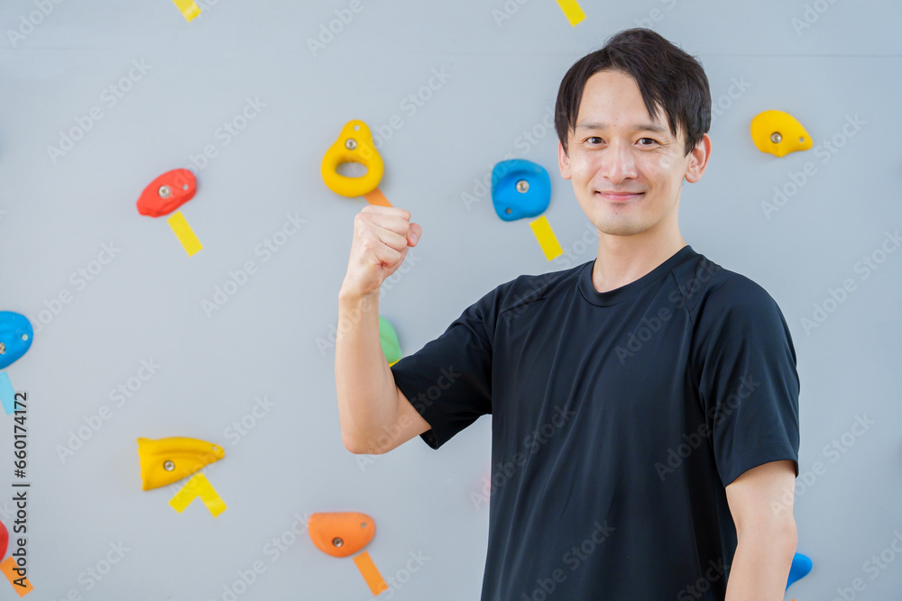 ボルダリングジムでガッツポーズをする男性