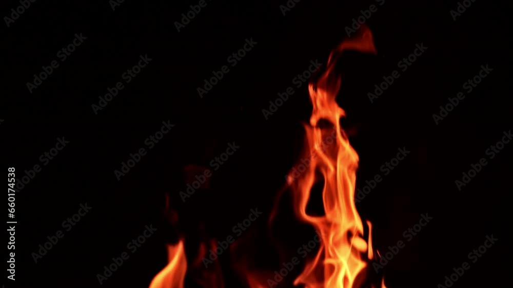 Tongues of orange flame rising up high. Tiny glaring sparkles fly up from bonfire. Black backdrop. Tongues of orange flame rising up high. Tiny glaring sparkles fly up from bonfire. Black backdrop.