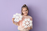 Cute little girl in knitted sweater with snowflakes on lilac background