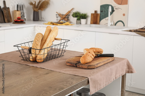 Cutting board with fresh baguette on table in interior of light kitchen