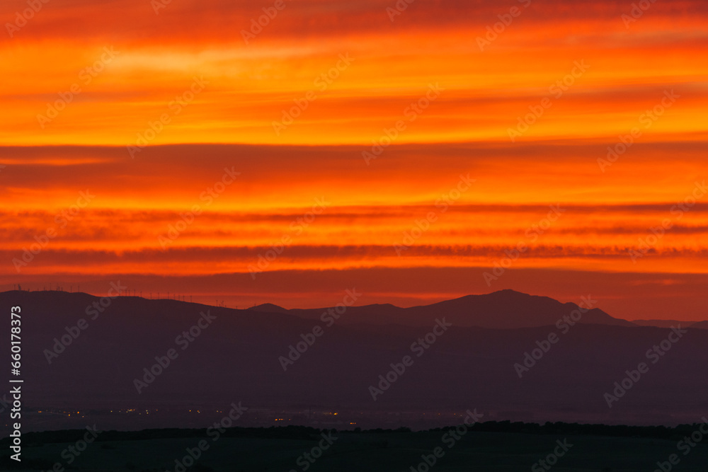 Orange warm colorful sky from sunset over silhouette of mountain landscape