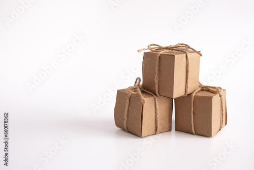 Three gift cube boxes made of kraft paper on an isolated white background. Brown parcel boxes tied with twine. Copy space
