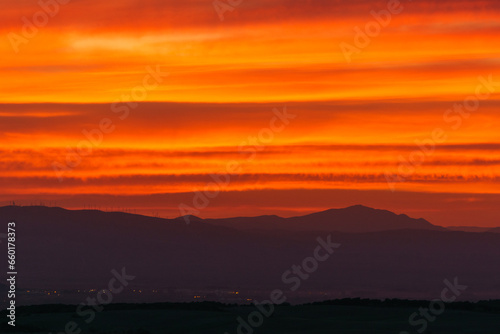 Orange warm colorful sky from sunset over silhouette of mountain landscape