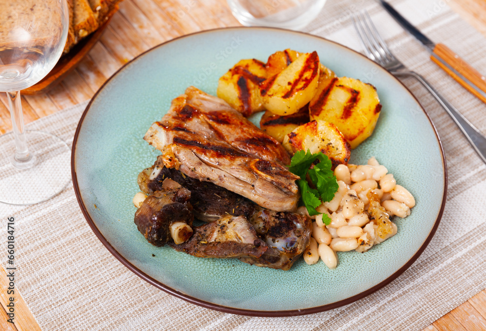 Grilled lamb with beans and roasted potato served with bread.