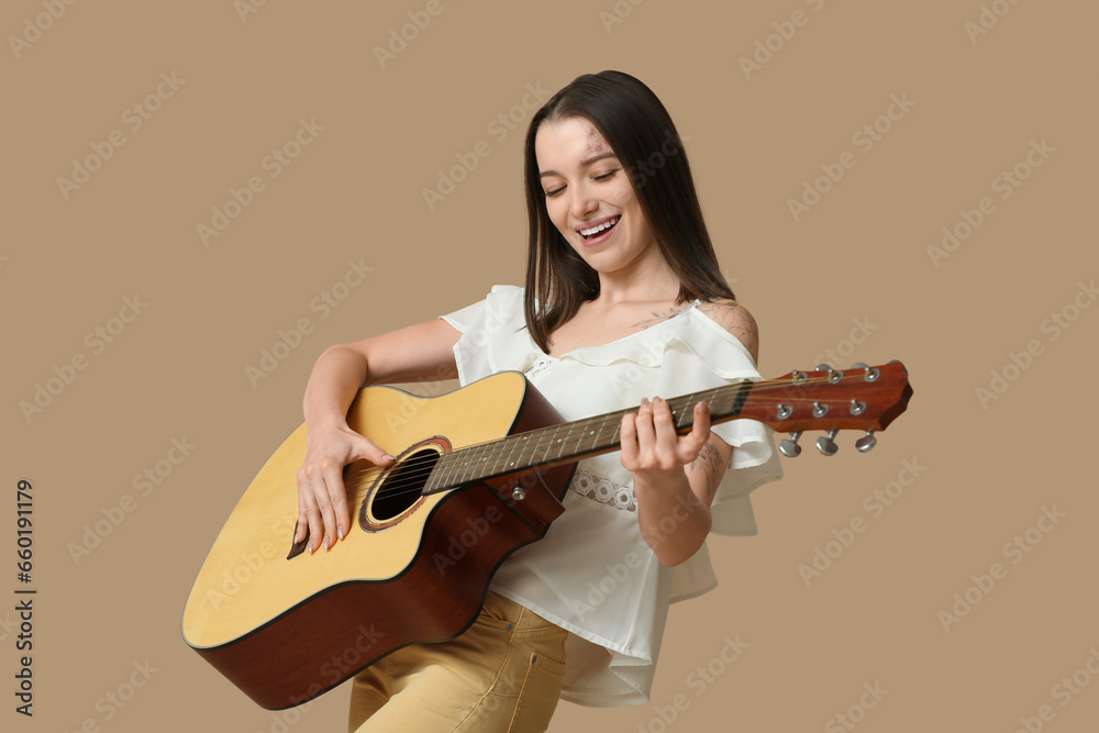 Pretty young woman playing acoustic guitar on beige background Pretty young woman playing acoustic guitar on beige background