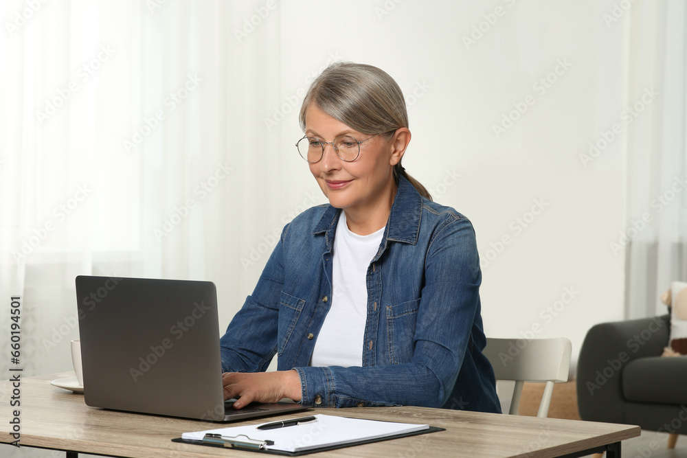 Beautiful senior woman using laptop at wooden table indoors Beautiful senior woman using laptop at wooden table indoors