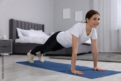 Happy woman doing plank exercise at home. Morning routine