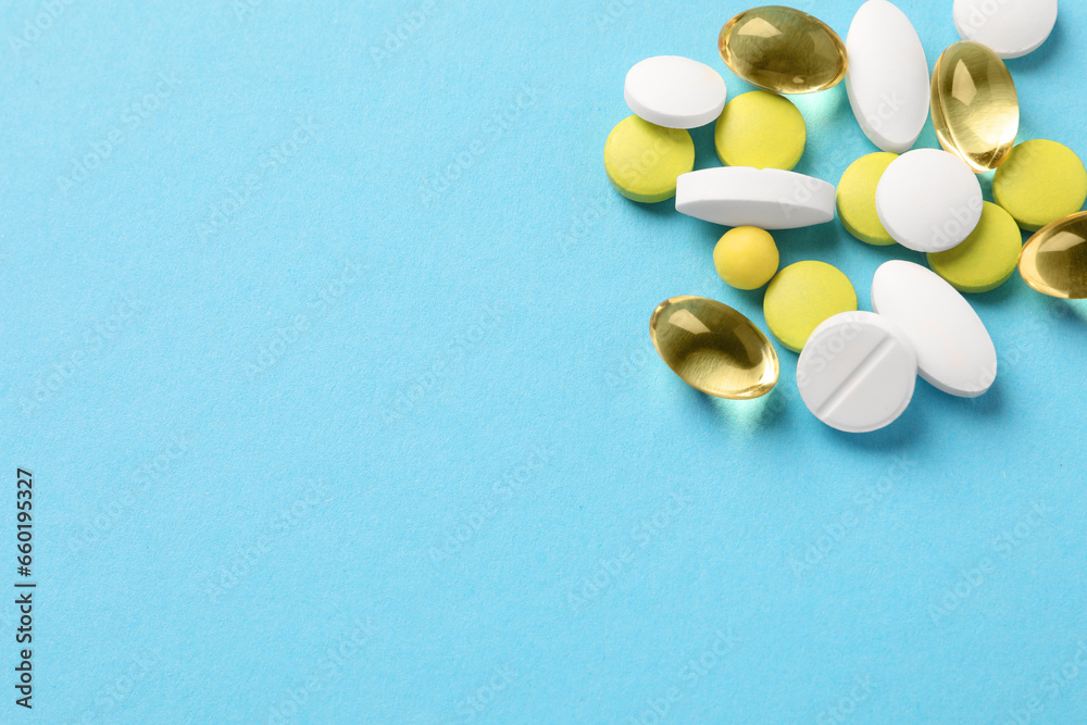 Pile of different pills on light blue background, flat lay. Space for text Pile of different pills on light blue background, flat lay. Space for text