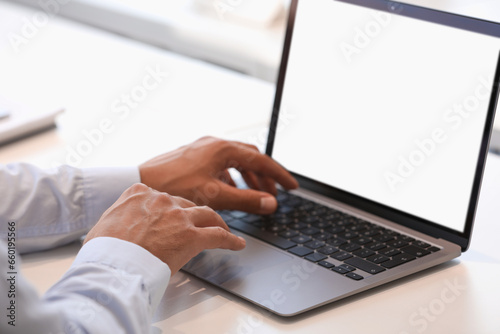 Man using modern laptop at white desk, closeup