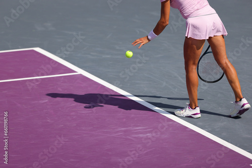 Female tennis player in action on the court on a sunny day, preparing to serve