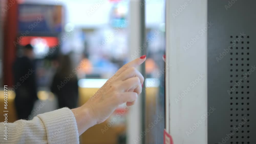 Girl using touch terminal makes a quick order through the self-service. Woman choosing dessert via self-service machine at fast food restaurant. Person swipes the screen making an order. Girl using touch terminal makes a quick order through the self-service. Woman choosing dessert via self-service machine at fast food restaurant. Person swipes the screen making an order.