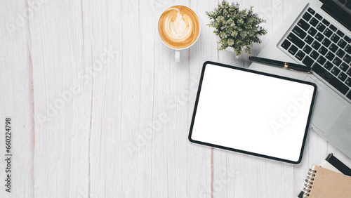 White wooden desk workplace with blank screen tablet, laptop, pen, notebook and cup of coffee, Top view flat lay with copy space.