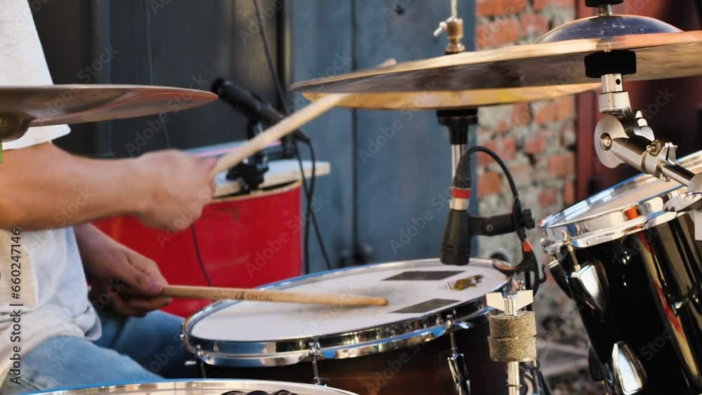 Close-up of man playing behind drum kit. The guy is playing a fast energetic part. Live performance at a rock concert. The concept of creativity