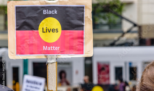 A homemade protest sign with a 'Black Lives Matter' political message on the aboriginal flag is held up by a wooden post © Adam Calaitzis