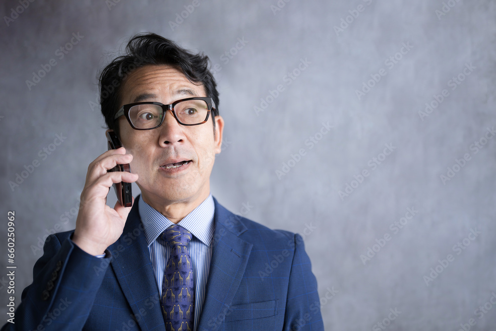 スマートフォンで電話をかけるビジネスマン　ハッとして気になる表情