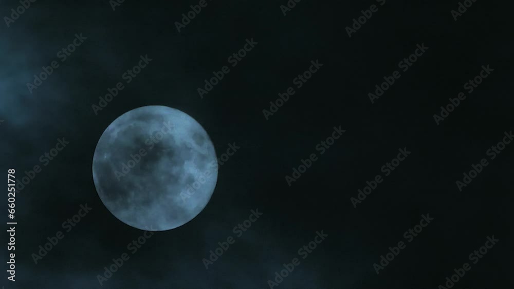 Clouds passing by the hollow bright moon. Clouds on a full moon. Close-up. Blank space for text. Mysterious and gloomy scene