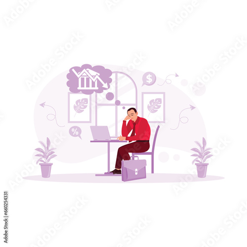 Sad middle-aged businessman sitting in front of the laptop. Calculating declining finances. Sitting near a pile of bills and feeling stressed. Financial Instability concept. 