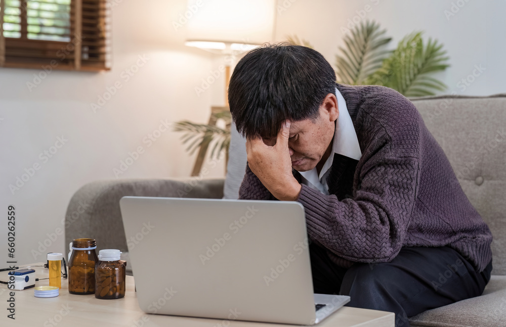 An elderly man with a headache is studying information about a medicine before taking it. Stressed elderly man Find drug information on your laptop An elderly man with a headache is studying information about a medicine before taking it. Stressed elderly man Find drug information on your laptop