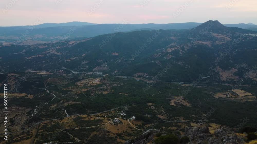 A drone rises above the stone peaks of a mountain, revealing a wide valley. A drone rises above the stone peaks of a mountain, revealing a wide valley.