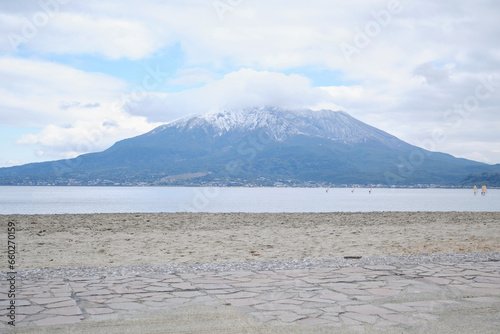 砂浜の先に見える雪が積もった桜島