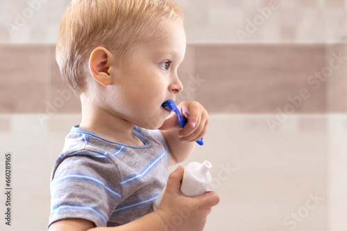 Toddler boy holds toothpaste and toothbrush in his hands. Child brushing teeth in the bathroom