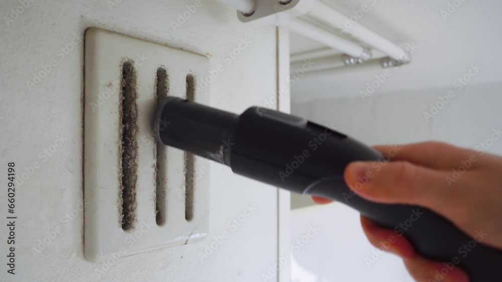 Man cleaning off the dust from an air vent with a vacuum cleaner. Close up