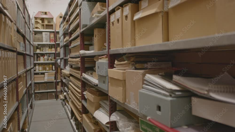 Pan over aisle of archive with cardboard boxes and files