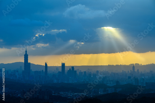 At dusk  the sun breaks through the clouds and shines on Taipei City. Silhouettes of city buildings. Orange sky and dark clouds.