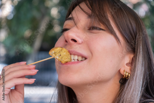 Closeup of a young woman eating baked potato outdoor