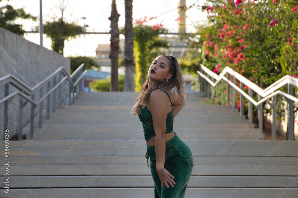 Obraz premium Latin and Hispanic girl, young and beautiful, dancing modern dance in the street outdoors. Dance concept, moonwalk, jumpstyle, shuffle, electrodance, hip hop, funky, popping.