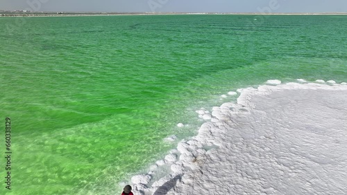 A woman in red dress standing by green salt lake