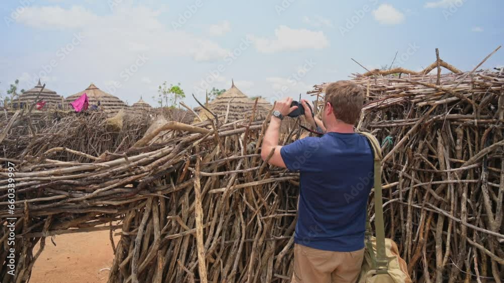 Caucasian documentary photographer takes pictures of village of Karamojong or Karimojong in Karamoja region, Uganda in Africa Caucasian documentary photographer takes pictures of village of Karamojong or Karimojong in Karamoja region, Uganda in Africa