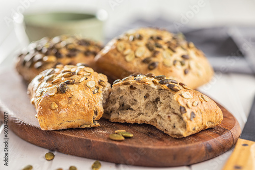 Whole grain bun with pumpkin seeds on cutting board.