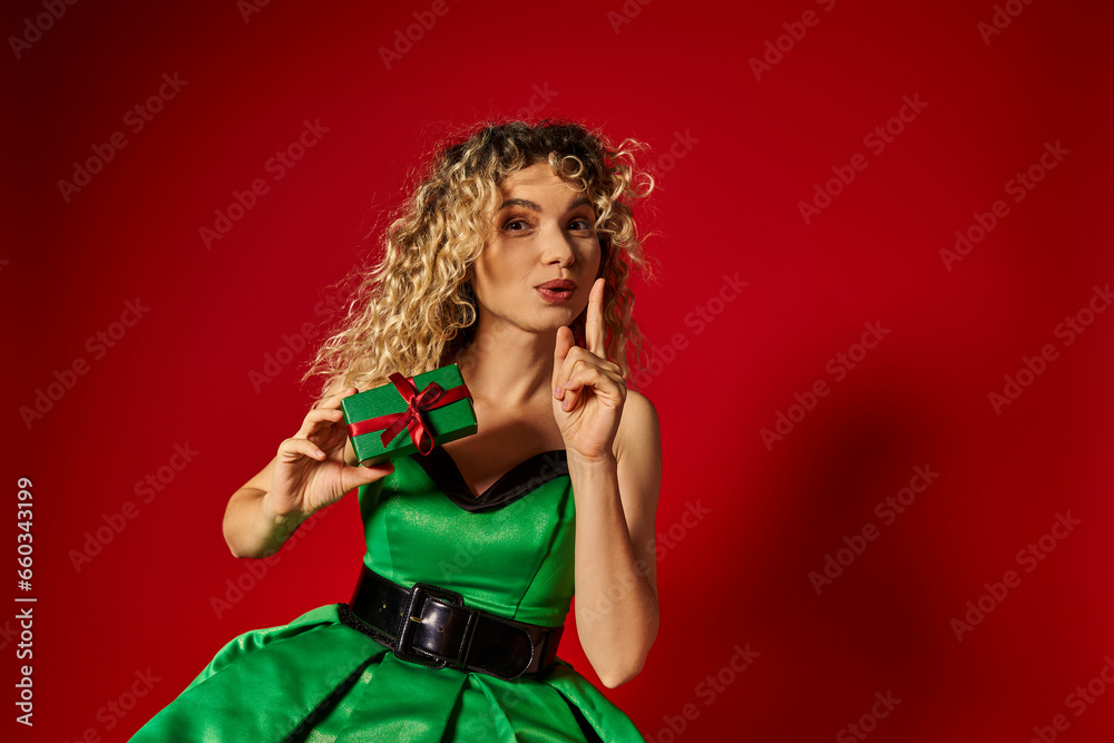 attractive new year elf in green dress showing silence gesture mysteriously with gift in hands attractive new year elf in green dress showing silence gesture mysteriously with gift in hands