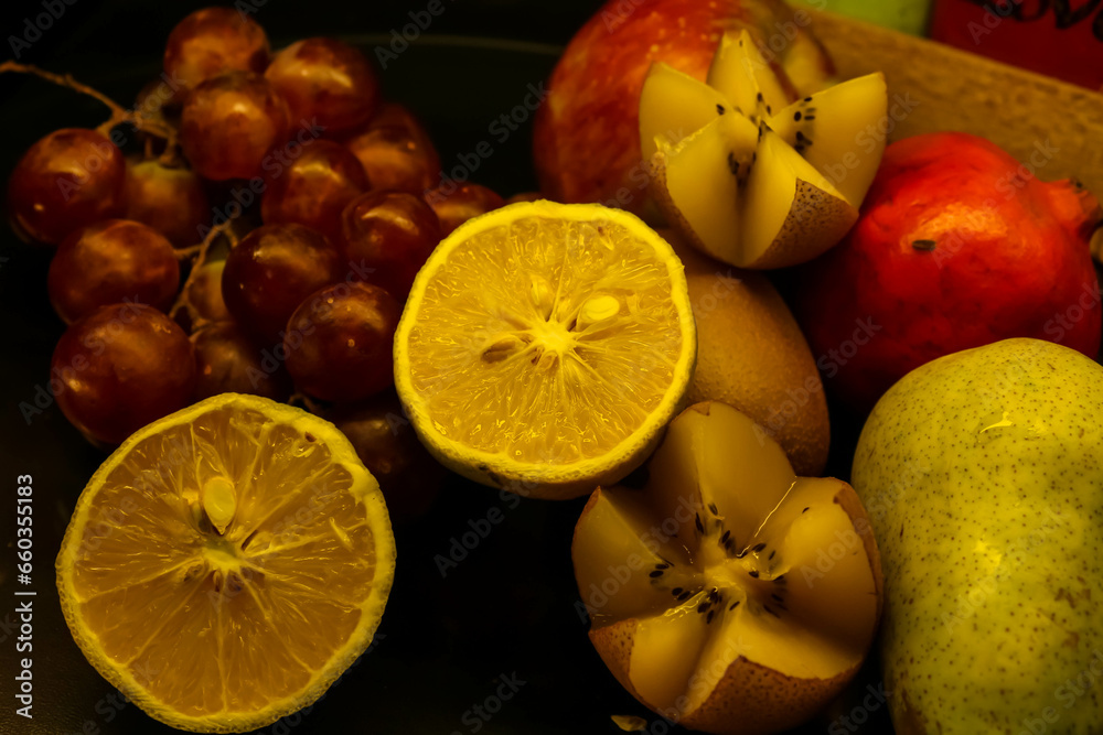 Fresh exotic Fruits (Kiwi, grapes, pear) on a black plate, close-up, selective focus Fresh exotic Fruits (Kiwi, grapes, pear) on a black plate, close-up, selective focus