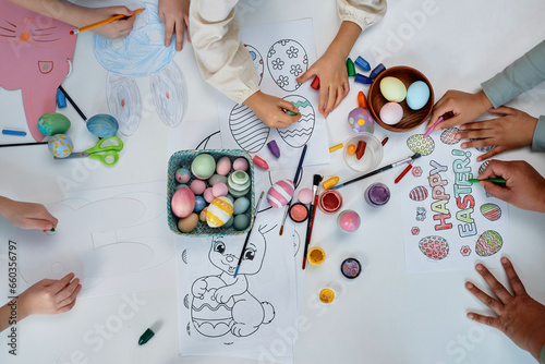 Top view of children coloring Easter pictures while celebrating Spring holidays in preschool, copy space