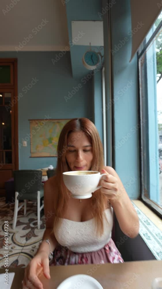 Mujer de pelo cobrizo tomando un cafe con leche grande durante el dia