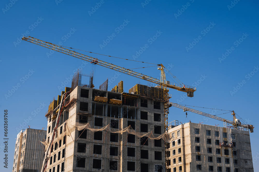 construction crane is building a residential building on a construction site against a blue sky background