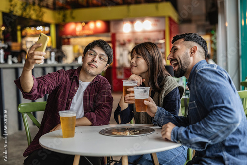 Group of smiling friends drinking and toasting beer at restaurant bar - Friendship concept with happy young people having fun together toasting beer at happy hour.