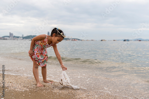 Little girl cleaning plastic bag on the beach.