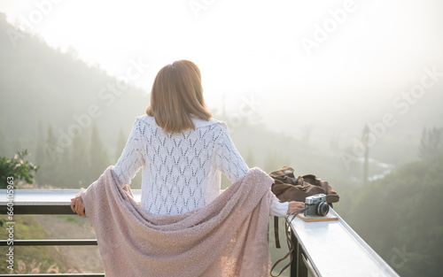 asian woman stands with her back to camera and enjoys the view of forest. and looking mountain view in morning sunrise with copy space. trip and relaxing. Travel vacations and lifestyle concept.