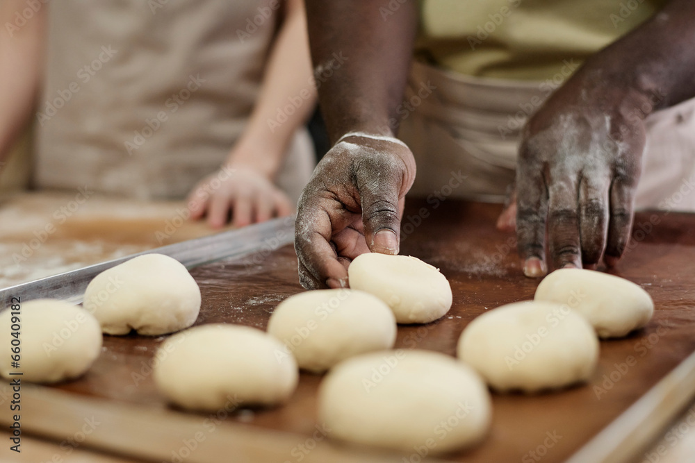 Close up of man carefully shaping dough for buns while working in artisan bakery, copy space Close up of man carefully shaping dough for buns while working in artisan bakery, copy space
