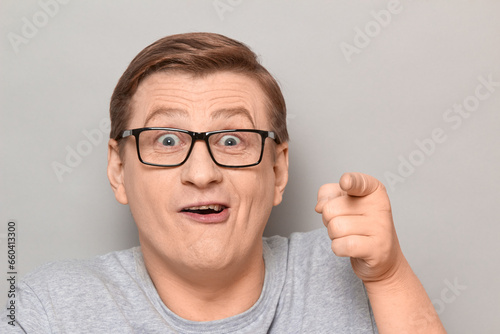 Portrait of funny cheerful man pointing with index finger at something
