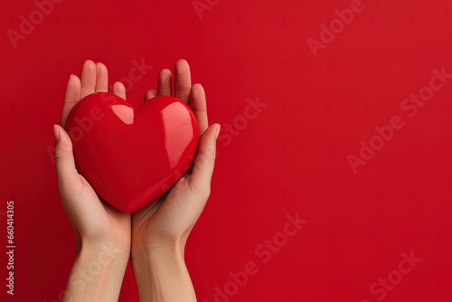 hand holds a red heart love shape on a red background with copy space