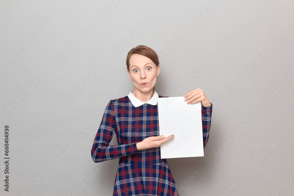 Portrait of surprised young woman holding white blank paper sheet Portrait of surprised young woman holding white blank paper sheet