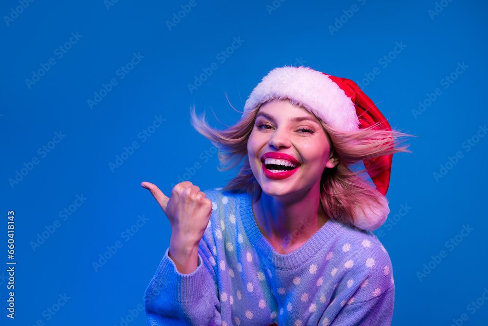 Photo of positive lovely girl stylish ugly sweater laughing demonstrating blank space promo isolated on neon light blue color background Photo of positive lovely girl stylish ugly sweater laughing demonstrating blank space promo isolated on neon light blue color background